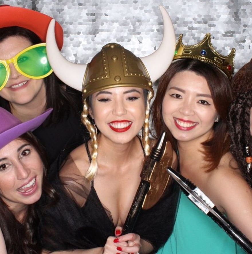 A group of girls taking a photo booth picture wearing various props