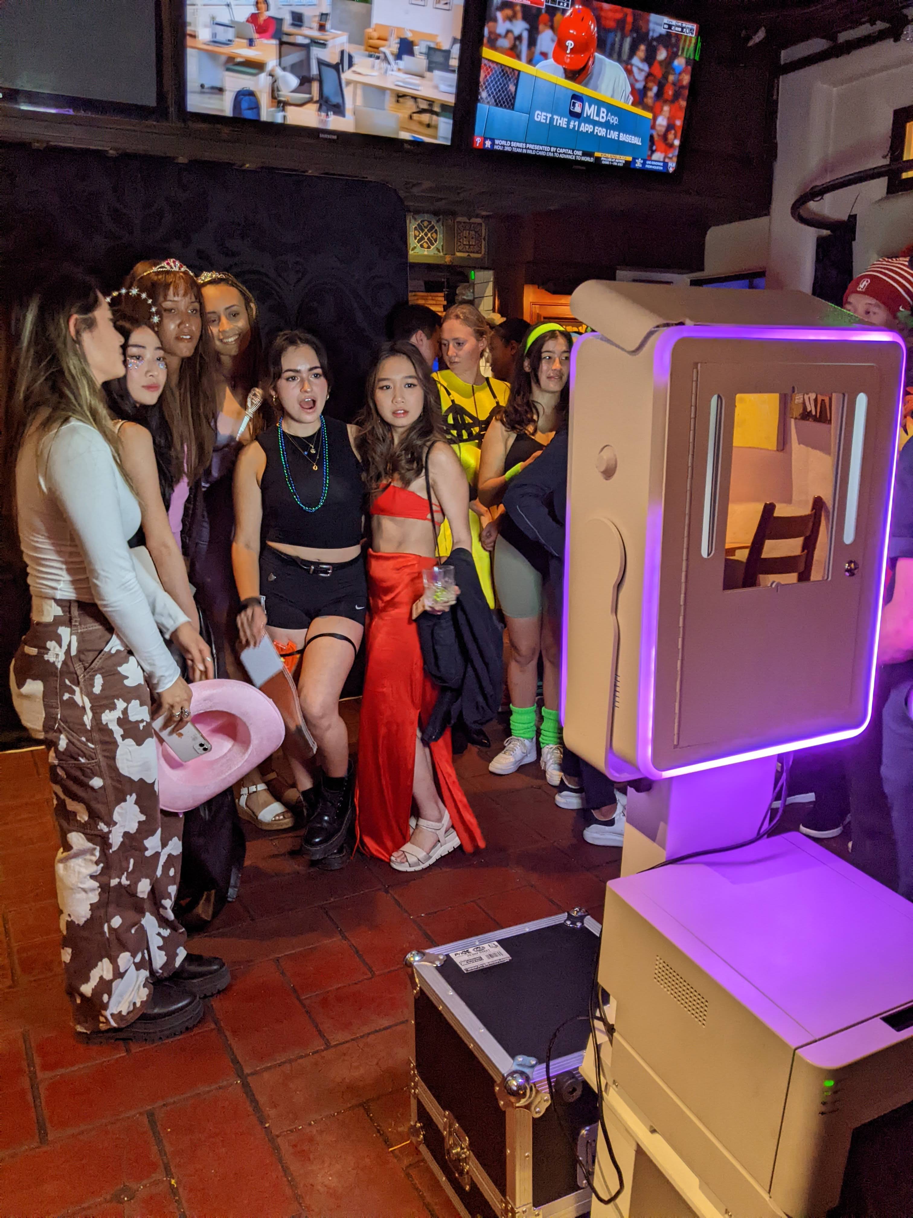 A group of students wearing Halloween costumes having their picture taken in the photo booth
