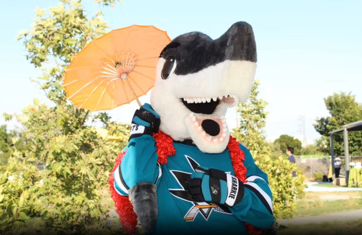 Sharky from the San Jose Sharks taking a selfie while using a photo prop umbrella
