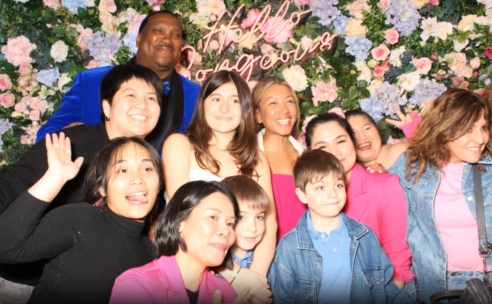 A group of people taking a photo in front of a floral backdrop